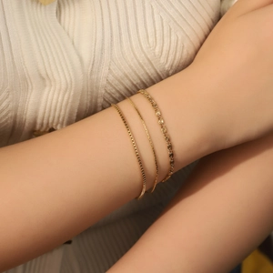 Close-up of a three-piece gold-plated titanium steel chain bracelet set on a model's wrist