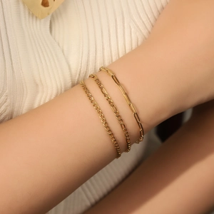 Detailed view of 3-piece set 18K gold plated stainless steel thin chain bracelets on wrist