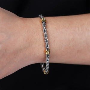 Detail of men's stainless steel rope chain bracelet with gold ring accents on wrist