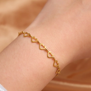 Close-up of a gold-plated stainless steel bracelet featuring hollow heart-shaped links on a wrist
