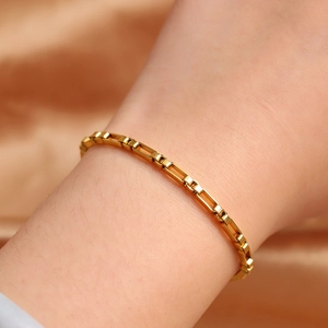 Macro shot of an 18K gold-plated stainless steel box chain bracelet on a model's wrist