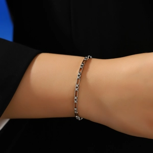 Close-up detail of silver stainless steel box chain bracelet worn on a female wrist