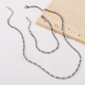 Detailed shot of stainless steel box chain necklace and bracelet set on a stone prop