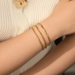 Detailed view of three layered 18K gold-plated stainless steel chains on a female wrist