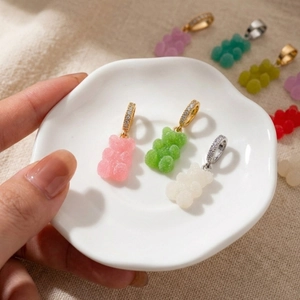 Colorful resin gummy bear pendants with sparkling crystal bail on a ceramic tray
