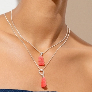 Detailed view of layered silver chains with pink gummy bear charms and heart clasp