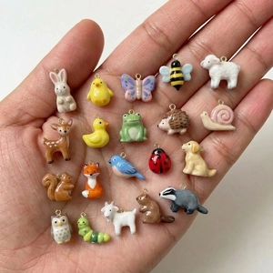 20 ciondoli animali assortiti placcati in oro 18K tra cui coniglio e cervo su un palmo