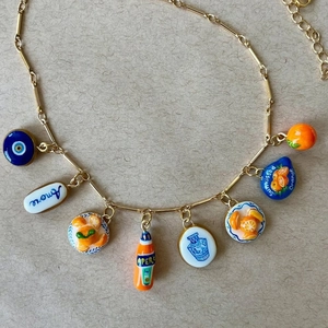 Golden stainless steel necklace with colorful charms like blue evil eye and fruit pendants