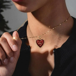 Vintage gold necklace with red enamel heart pendant and eye motif on a model
