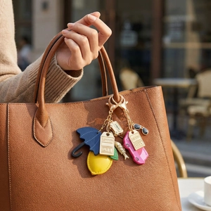 Colorful multi-element keychain charm with umbrella and London luggage tags on a brown bag