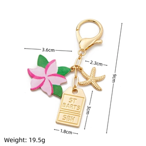 Detail of colorful gold keychain with pink flower, starfish, and ST BARTS engraved tag