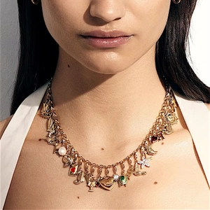 Detalle de collar vintage dorado con dijes que incluyen letras y conchas marinas