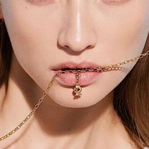 Primer plano del collar dorado con un colgante de caramelo rojo usado por una modelo