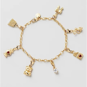 Detalle de una pulsera dorada con siete dijes diversos y un cierre de mosquetón