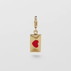 Detalle de un colgante de sobre bañado en oro con corazón rojo y cierre de langosta
