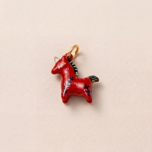 Détail d'un pendentif licorne rouge peint à la main avec fermoir en métal doré 18 carats