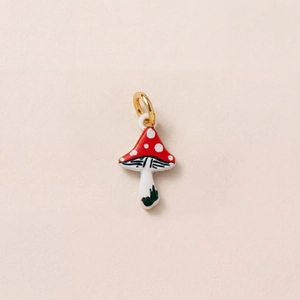 Détail d'un pendentif champignon rouge et blanc avec un anneau de connexion doré