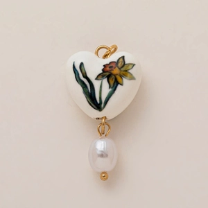 Vue détaillée du pendentif cœur en céramique blanche avec motif fleur et perle