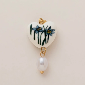 Détail du pendentif en céramique cœur avec motif floral bleu et perle goutte