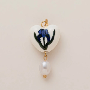 Détail du pendentif en céramique en forme de cœur avec motif floral et perle blanche