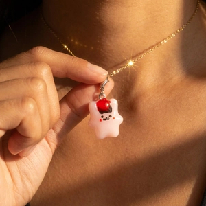 Primer plano de un colgante de estrella rosa con cadena dorada en el cuello del modelo