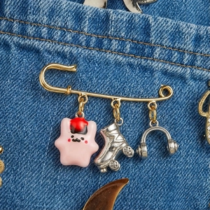Broche imperdible chapado en oro 18K con colgantes de estrella rosa, patín y auriculares