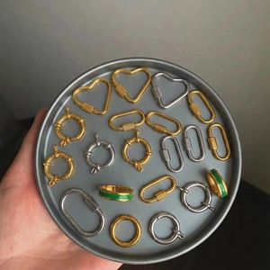 Assorted gold and silver stainless steel jewelry connectors in a round metal tray