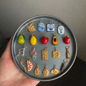 Assorted 18K gold plated stainless steel fruit and flower pendants on a metal tray