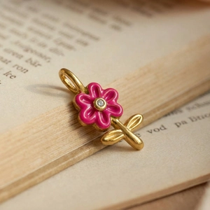 Detailed macro shot of 18K gold plated pink enamel flower pendant on vintage paper