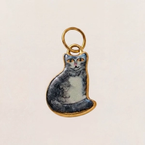 Detailansicht eines goldenen Edelstahl-Katzenanhängers mit grau-weißer Emaille-Veredelung