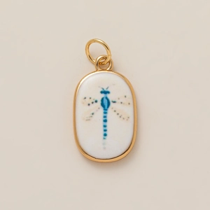 Oval gold plated charm with white ceramic inlay and artistic blue dragonfly pattern