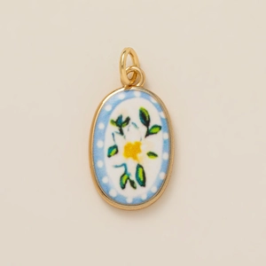 Vintage oval gold pendant with blue polka dot ceramic background and floral motif