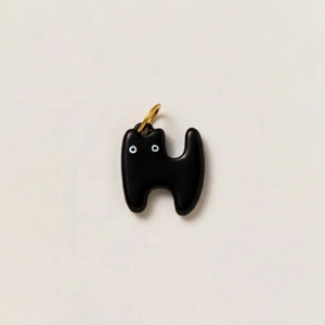 Detail eines minimalistischen schwarzen Katzenanhängers aus Emaille mit goldener Öse