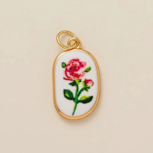 Oval gold-plated charm with white ceramic base and delicate pink rose flower pattern