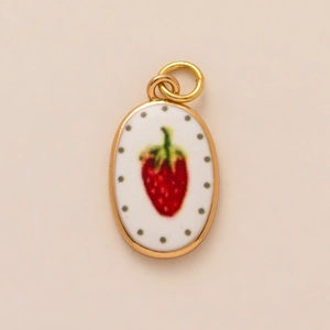 Oval gold plated charm with white enamel strawberry pattern and green dots