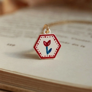 French retro style hexagonal tulip pendant with golden chain shown on an open book