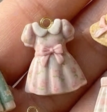 Makro-Detail eines rosa geblümten Kleideranhängers mit goldenem Ring am Finger