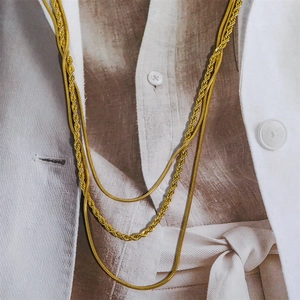 Detailed macro view of layered gold snake and rope chains on a stylish magazine