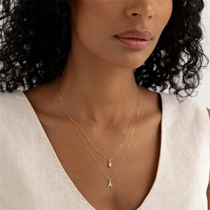 Close-up van dubbellaagse gouden ketting met marquise zirkoon en hanger met letter A