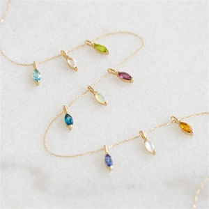 Gouden station ketting met veelkleurige marquise edelstenen op witte marmeren basis