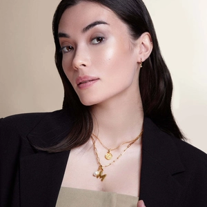 Collana a strati con moneta d'oro e ciondolo M indossata con orecchini a stella