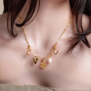 Gold multi-charm necklace featuring heart engraving, coin and star on paperclip chain