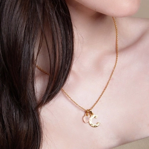 Collana dorata con ciondolo a cuore rosa e lettera C martellata indossata al collo