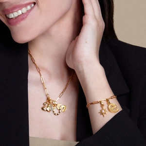 Primo piano di collana e bracciale dorati con ciondoli a cuore e geometrici