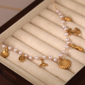 Detailansicht der Meeresanhänger mit goldenem Fischschwanz und Muschel auf Perlenkette