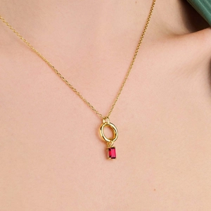 Detalle de collar con colgante de oro de 18K y rubí en una modelo femenina
