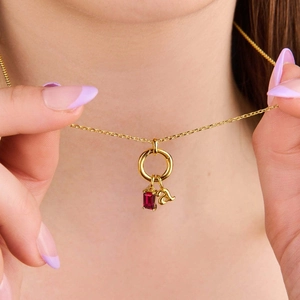 Detalle del collar chapado en oro de 18K con rubí y colgante de letra a minúscula