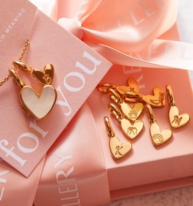 Primer plano de colgantes de corazón en oro de 18K con grabados e incrustación nácar