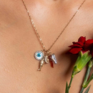 Gold plated stainless steel necklace with evil eye, fish, and horn charms on a model