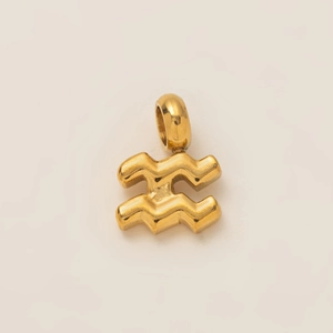 Close-up of golden Aquarius zodiac pendant with polished finish on beige background